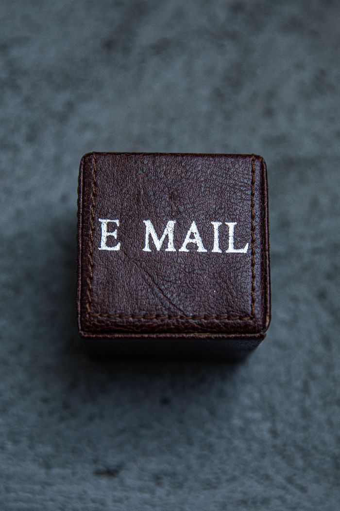 cta-bg Brown leather square box with E MAIL text on a gray surface, modern still life